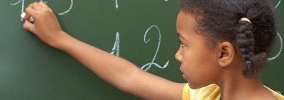 Girl solves math problem on chalkboard
